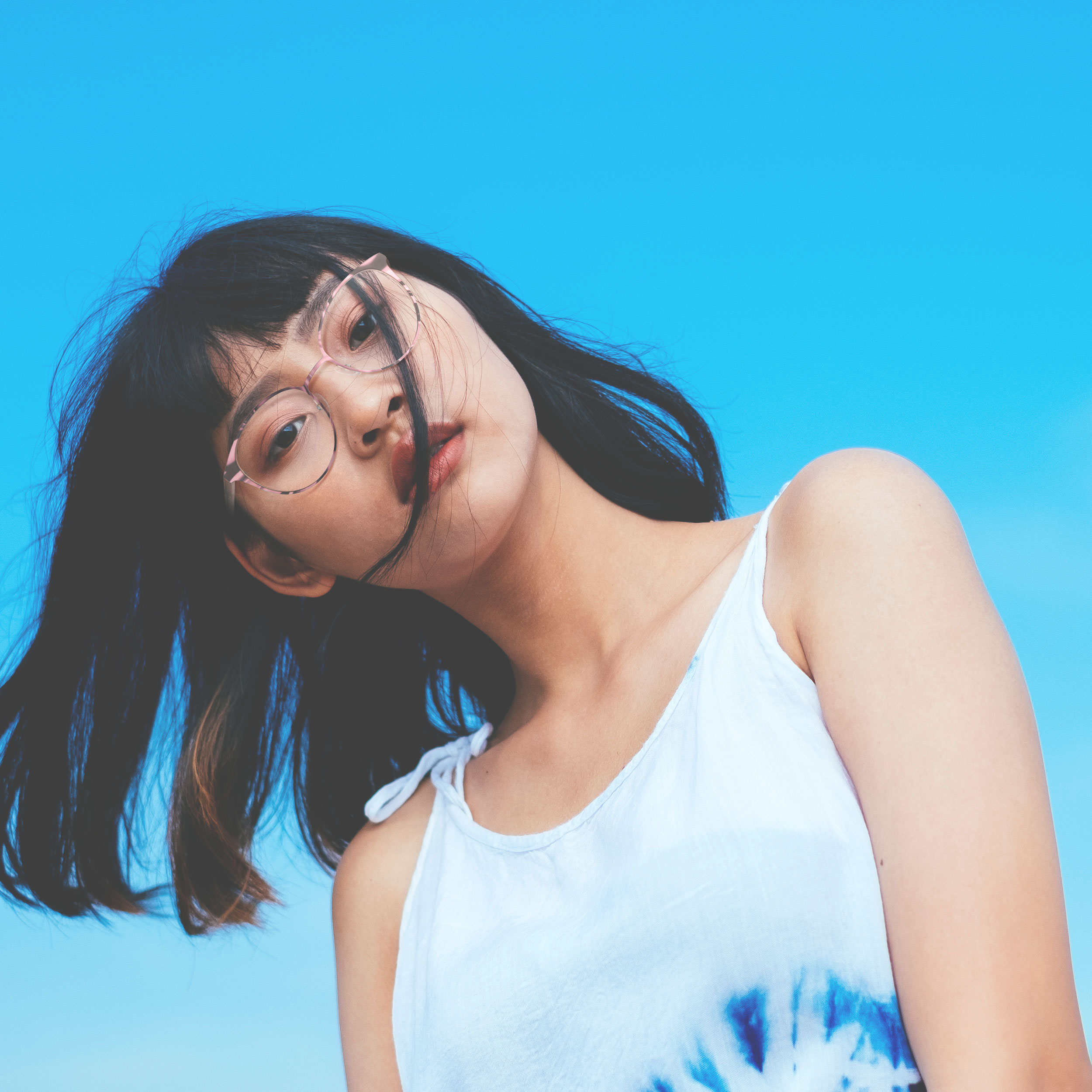 femme brune coupe carrée vue d'en bas, avec ciel derrière elle